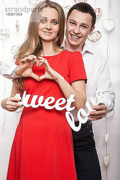 Schönes junges Paar in der Liebe mit den Worten Süße Liebe zeigt die Form des Herzens Hände. Valentinstag. Bild im Studio aufgenommen