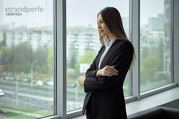 Schöne Geschäftsfrau steht nachdenklich am Fenster