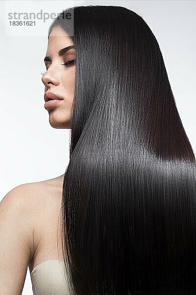 Schönes brünettes Mädchen in Bewegung mit einem perfekt glatten Haar  und klassisches Make-up. Schönheit Gesicht. Bild im Studio auf einem weißen Hintergrund genommen