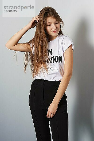 Attraktive Mode-Modell in Hosen und T-Shirt mit Inschrift berühren ihr Haar