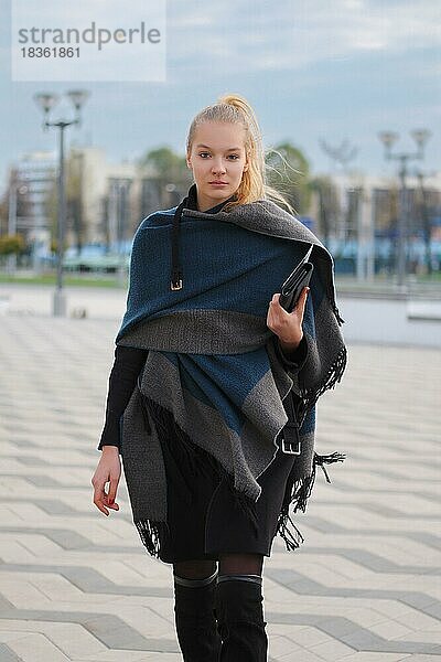 Hübsches Mädchen in warmen Wollmantel und Schal um den Hals gewickelt zu Fuß auf der Straße. Urbaner Stil Hipster