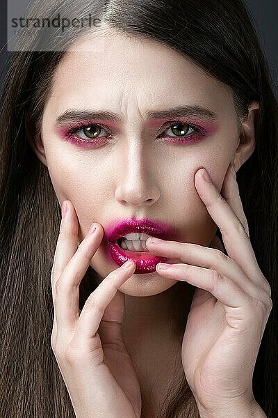 Mädchen mit rosa Lippenstift im Gesicht verschmiert. Kreatives Make-up. Bild im Studio aufgenommen