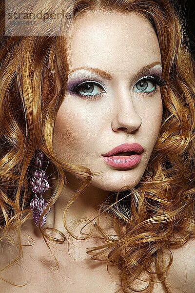 Schönes rothaariges Mädchen mit hellem Make-up und Locken. Bild im Studio auf einem schwarzen Hintergrund aufgenommen