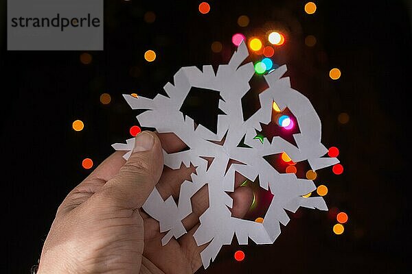 Schneeflocke geformt Papier in der Hand auf Bokeh Licht Hintergrund