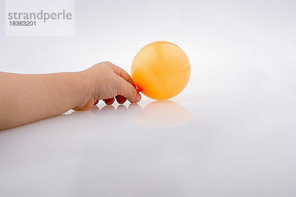 Hand hält einen bunten kleinen Ballon auf einem weißen Hintergrund