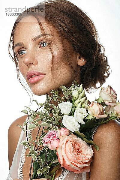 Schöne Frau mit klassischem Nackt-Make-up  heller Frisur und Blumen. Schönes Gesicht. Foto im Studio aufgenommen