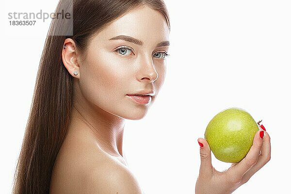 Schönes junges Mädchen mit einem leichten natürlichen Make-up und perfekter Haut mit Apfel in der Hand. Schönes Gesicht. Bild im Studio auf einem weißen Hintergrund genommen