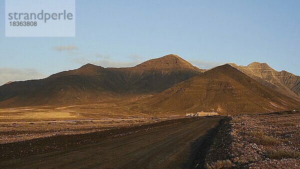 Morgenlicht  Wilder Süden  Jandia  karge Landschaft  nicht-asphaltierte Straße  rotbraune Hügel  blauer Himmel  wenige Wolken  Fuerteventura  Kanarische Inseln  Spanien  Europa