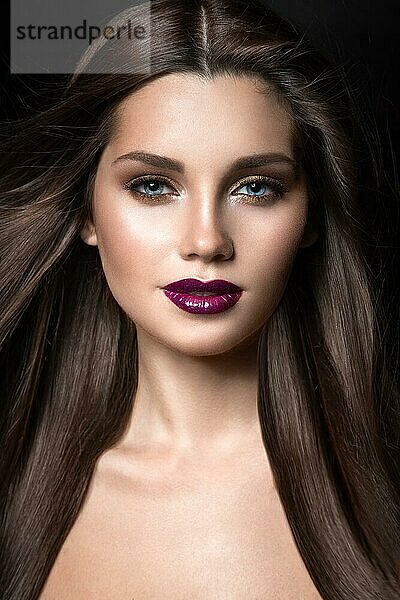 Schönes Mädchen mit goldenem Make-up und weinroten Lippen mit dem Wind im Haar. Schönheit Gesicht. Bild im Studio auf einem schwarzen Hintergrund genommen