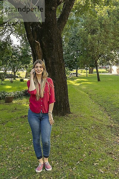 Junge blonde Frau beim Telefonieren im Park