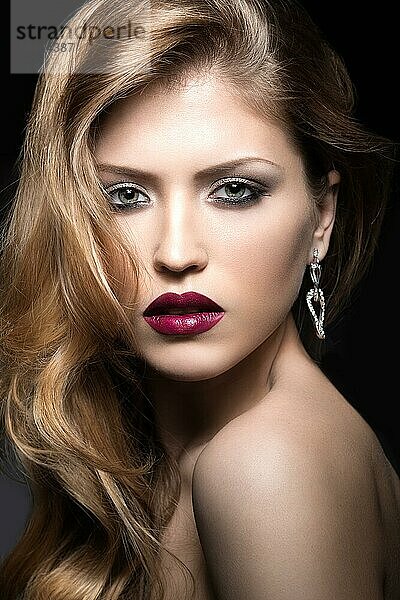 Schönes Mädchen mit roten Lippen und klassischem Make-up und Locken. Schönes Gesicht. Foto im Studio aufgenommen