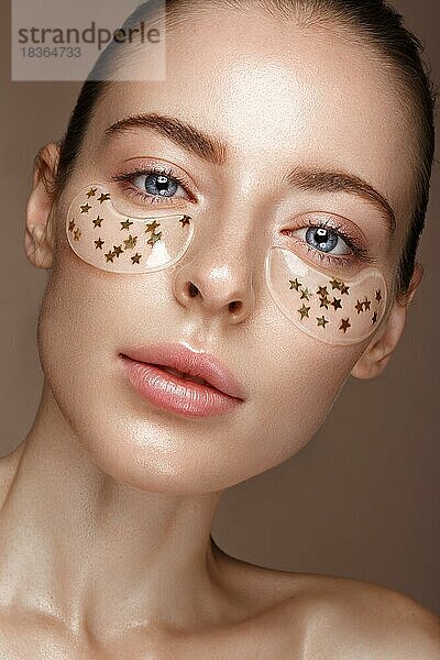 Schöne frische Mädchen mit kosmetischen Flecken unter den Augen  perfekte Haut und natürliches Make-up. Schönes Gesicht. Foto im Studio aufgenommen