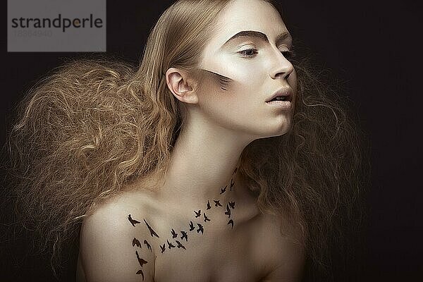 Schönes Mädchen mit einem Muster auf dem Körper in Form von Vögeln  kreative Make-up und Frisur üppig. Schönheit Gesicht. Bild im Studio auf einem grauen Hintergrund genommen