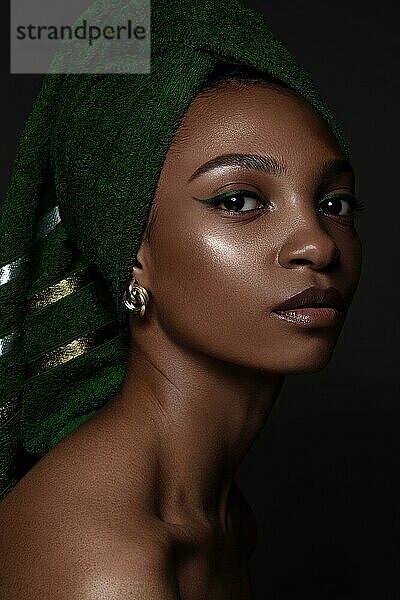 Schöne schwarze Frau mit einem grünen Handtuch auf dem Kopf und klassischem Make-up. Schönes Gesicht. Foto im Studio aufgenommen