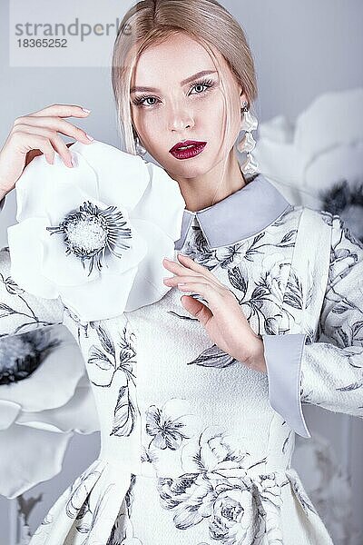Schönes Mädchen mit Vintage-Make-up und Frisur in einem warmen Winter Wollkleid. Dekoration von Blumen. Die Schönheit des Gesichts. Fotos im Studio geschossen