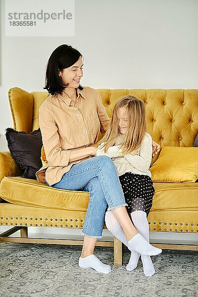 Lifestyle-Foto von Mutter und Tochter zu Hause auf dem Sofa