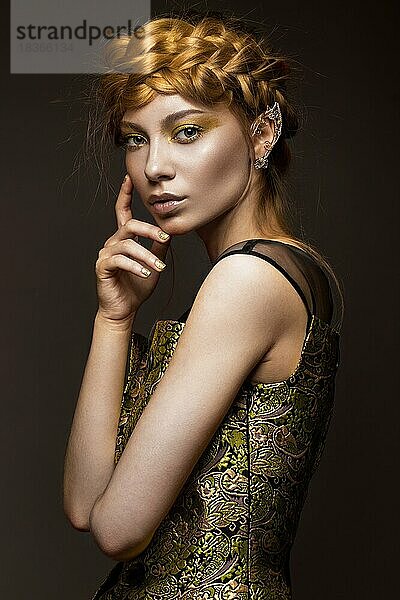 Schönes Mädchen in einem goldenen Kleid mit kreativem Make-up und Zöpfen auf dem Kopf. Die Schönheit des Gesichts. Fotos im Studio geschossen