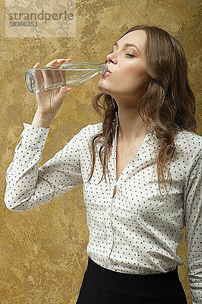 Porträt eines attraktiven Mädchens  das reines Wasser aus einer Flasche trinkt