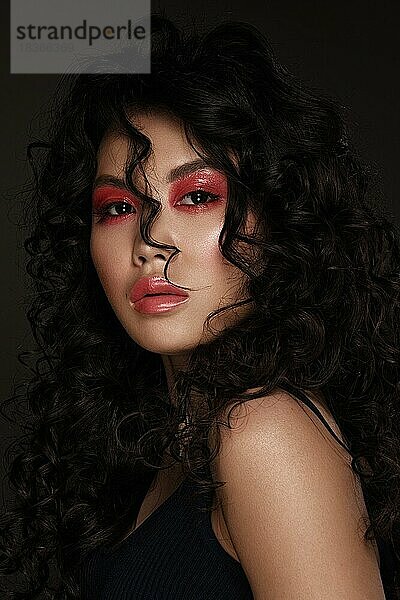 Porträt einer schönen asiatischen Frau mit rotem Make-up und Locken. Beauty face.photo im Studio aufgenommen