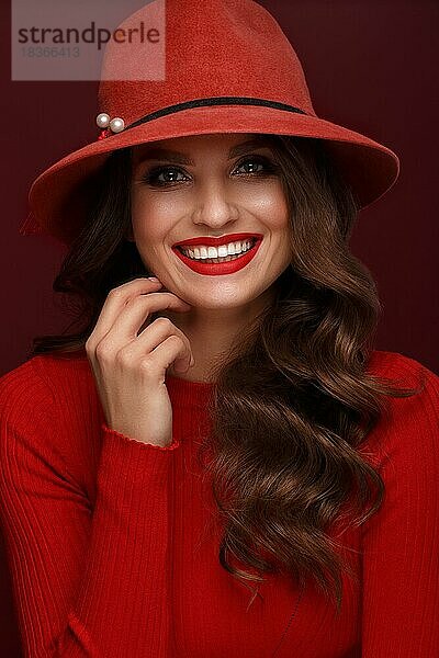 Schöne sexy Frau in einem modischen Hut  mit klassischem Make-up  Wellenhaar und roten Lippen. Schönes Gesicht. Foto im Studio aufgenommen