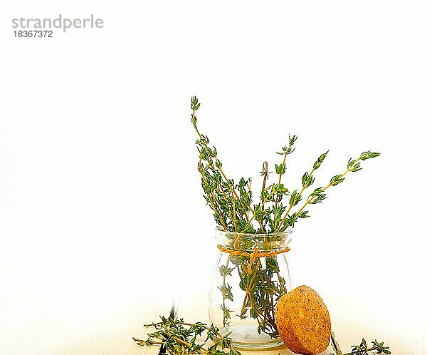 Frischer Thymian in einem Glasgefäß über einem rustikalen Tisch aus weißem Holz