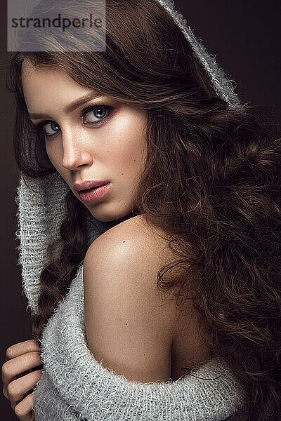 Schönes junges Mädchen mit sanftem Make-up im warmen Pullover und langen glatten Haaren. Schönes Gesicht. Studio Porträt