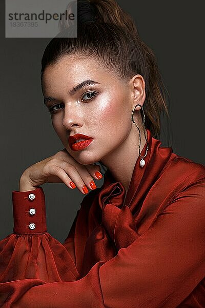 Schönes frisches Mädchen mit klassischem Make-up  glatten Haaren in einem roten Kleid. Schönes Gesicht. Foto im Studio aufgenommen