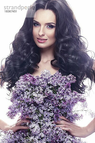 Schönes brünettes Mädchen mit einem sanften romantischen Make-up  rosa Lippen und Blumen. Die Schönheit des Gesichts. Porträtaufnahme im Studio