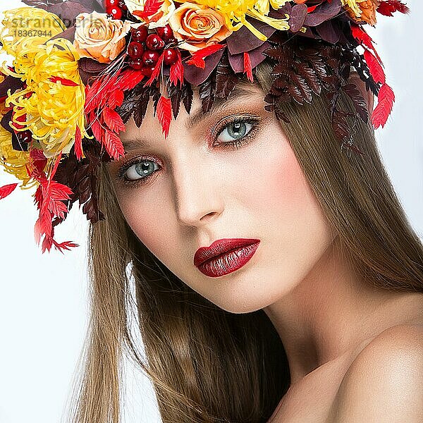Schönes Mädchen mit hellem Herbstkranz aus Blättern und Blumen. Schönes Gesicht. Bild im Studio auf einem weißen Hintergrund genommen