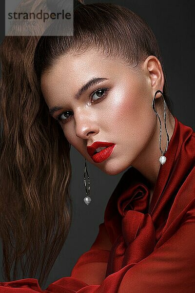 Schönes frisches Mädchen mit klassischem Make-up  glatten Haaren in einem roten Kleid. Schönes Gesicht. Foto im Studio aufgenommen