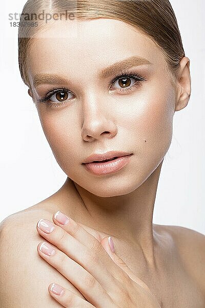 Schönes junges Mädchen mit einem leichten natürlichen Make-up und französischer Maniküre. Schönes Gesicht. Bild im Studio auf einem weißen Hintergrund aufgenommen