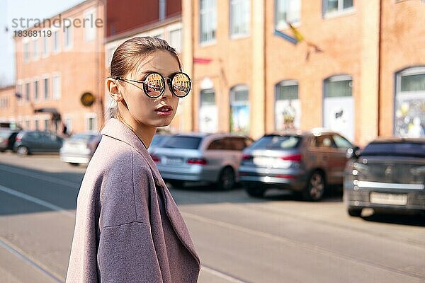 Junges Mädchen beim Überqueren der Straße. Spiegel Sonnenbrille mit Straße reflektiert in ihm