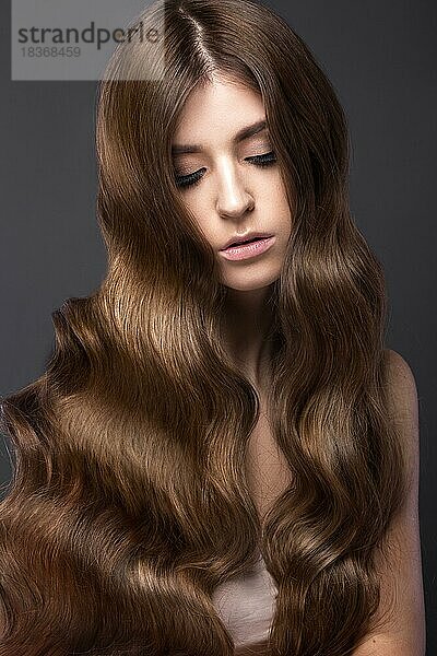 Schönes brünettes Mädchen mit perfekt gelocktem Haar und klassischem Make-up. Schönes Gesicht. Bild im Studio aufgenommen