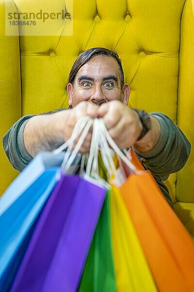 Glücklicher Mann mit Einkaufstüten auf gelbem Hintergrund. Freude am Konsum. Käufe  schwarzer Freitag  Rabatte  Verkauf Konzept