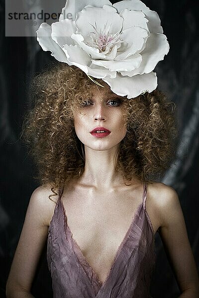 Schönes Mädchen mit lockigem Haar in Dessous mit großer Blume. Die Schönheit des Gesichts. Fotos im Studio geschossen