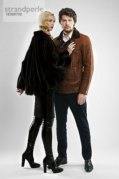 Stilvoller Mann und Glamour-Frau im Pelzmantel posieren im Studio