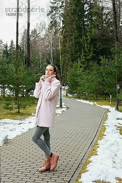 Hübsches Mädchen in rosa Mantel zu Fuß entlang Weg im Wald