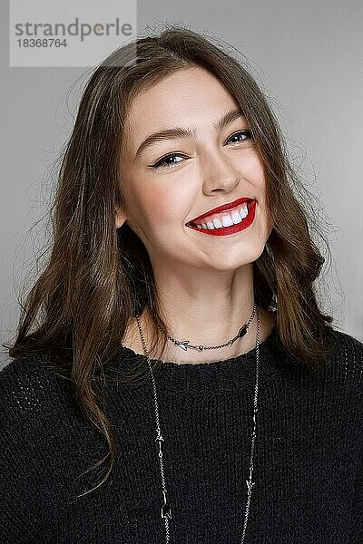Closeup-Portrait eines jungen lachenden Mädchens mit perfekter Haut und matten roten Lippen mit natürlichem Make-up und brünetten Haaren