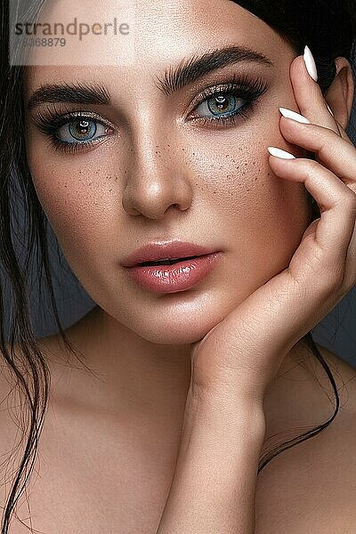 Schönes Mädchen mit hellen modischen Make-up  Sommersprossen und blauen Augen. Schönes Gesicht. Foto im Studio aufgenommen