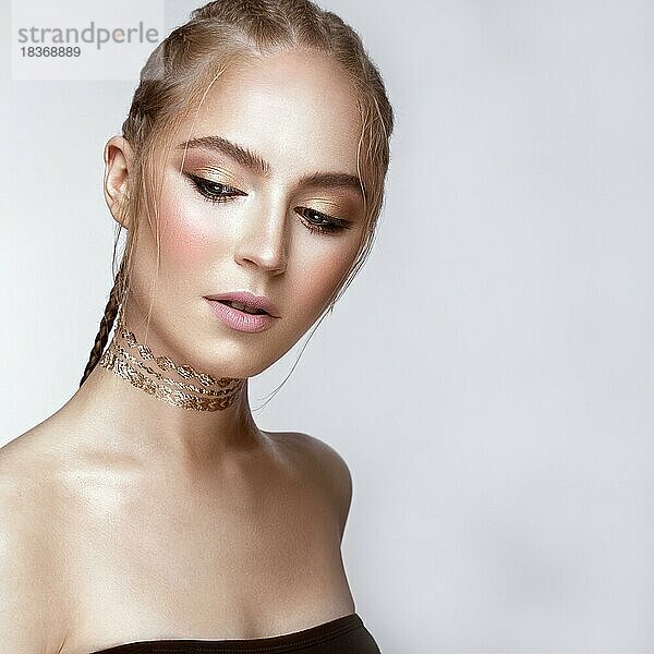 Schönes Mädchen mit einem goldenen glänzenden Make-up und einem Haarschnitt auf dem Kopf. Schönes Gesicht. Foto im Studio aufgenommen