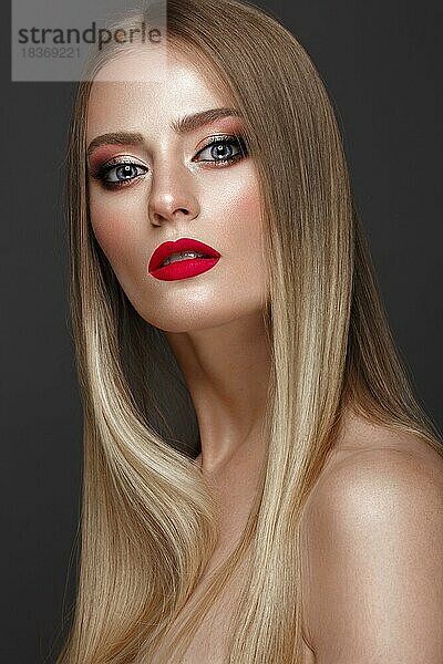 Schönes blondes Mädchen mit perfekt glattem Haar  klassischem Make-up und roten Lippen. Schönes Gesicht. Bild im Studio auf einem weißen Hintergrund genommen