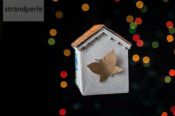 Papier Schmetterling auf einem Modell Haus auf einem Bokeh Licht