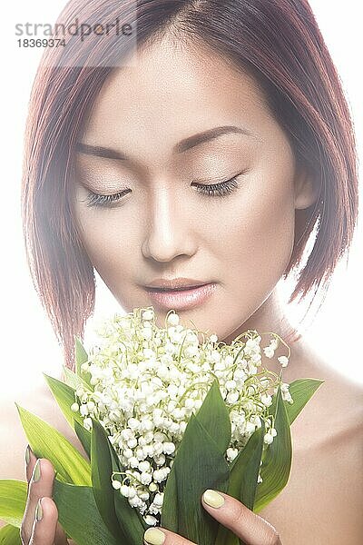 Mode schönes Mädchen orientalischen Typ mit zarten natürlichen Make-up und Blumen. Schönheit Gesicht. Bild im Studio auf einem weißen Hintergrund genommen
