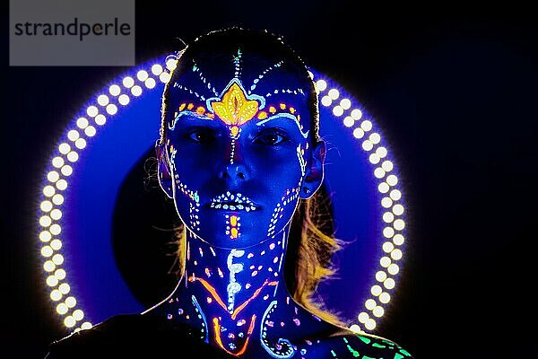 Porträt eines schönen Mädchens mit ultravioletter Farbe im Gesicht. Mädchen mit Neon-Make-up in Farbe Licht