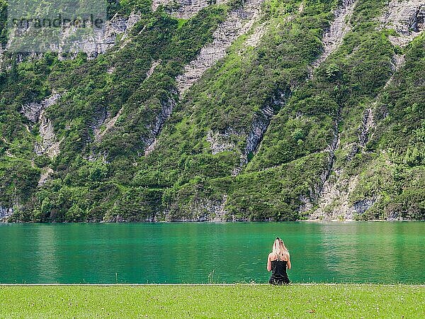 Junges Mädchen sitzend am Ufer des Achensees  Österreich  vor beeindruckendem Felsen  Europa