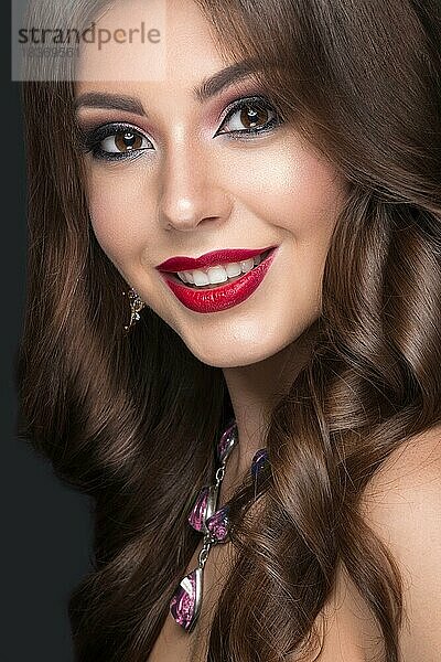 Schöne Frau mit arabischem Make-up  roten Lippen und Locken. Schönes Gesicht. Bild im Studio auf einem grauen Hintergrund genommen