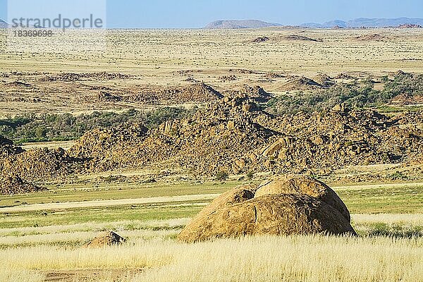 Orangefarbene Felsen und Gesteinsbrocken liegen verstreut in der wunderschönen Landschaft Namibias. Die Felsen leuchten wunderschön in der späten Nachmittagssonne. Damaraland  Namibia  Afrika