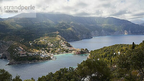 Dorf  Assos  Boote  Häuser  grüne Hügel  grau-weiße Wolken über den Bergen  Westküste  Insel Kefalonia  Ionische Inseln  Griechenland  Europa