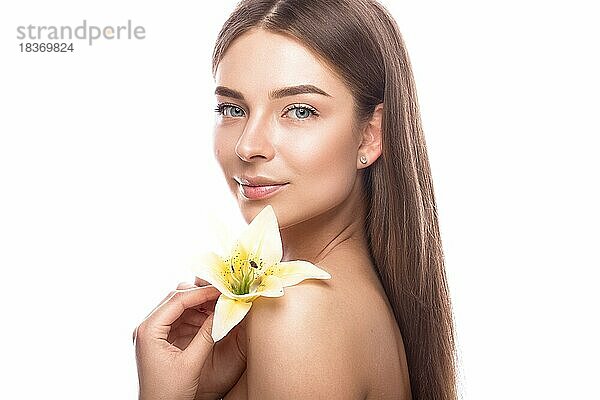 Schönes junges Mädchen mit einem leichten natürlichen Make-up und perfekter Haut mit Blumen in der Hand. Schönes Gesicht. Bild im Studio auf einem weißen Hintergrund aufgenommen