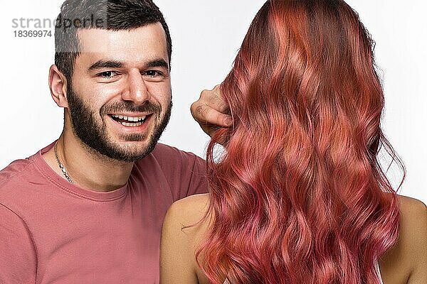 Friseur und schönes rosa Mädchen mit perfekt glattem Haar und klassischem Make-up. Schönes Gesicht. Bild im Studio aufgenommen